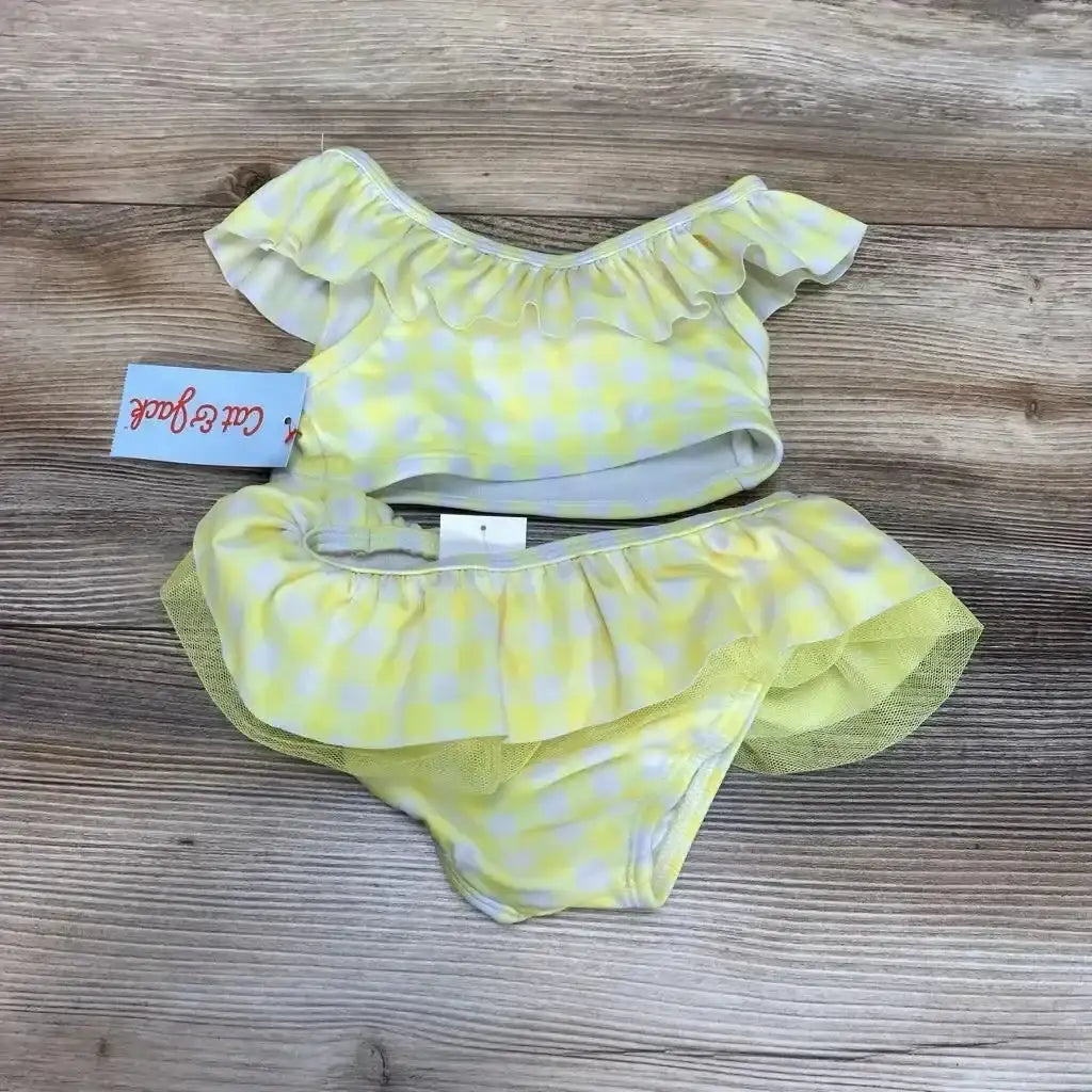 Top-down view of yellow gingham 2-piece toddler bikini (size 18M) with ruffled off-shoulder top and tulle-trim bottoms on wood background