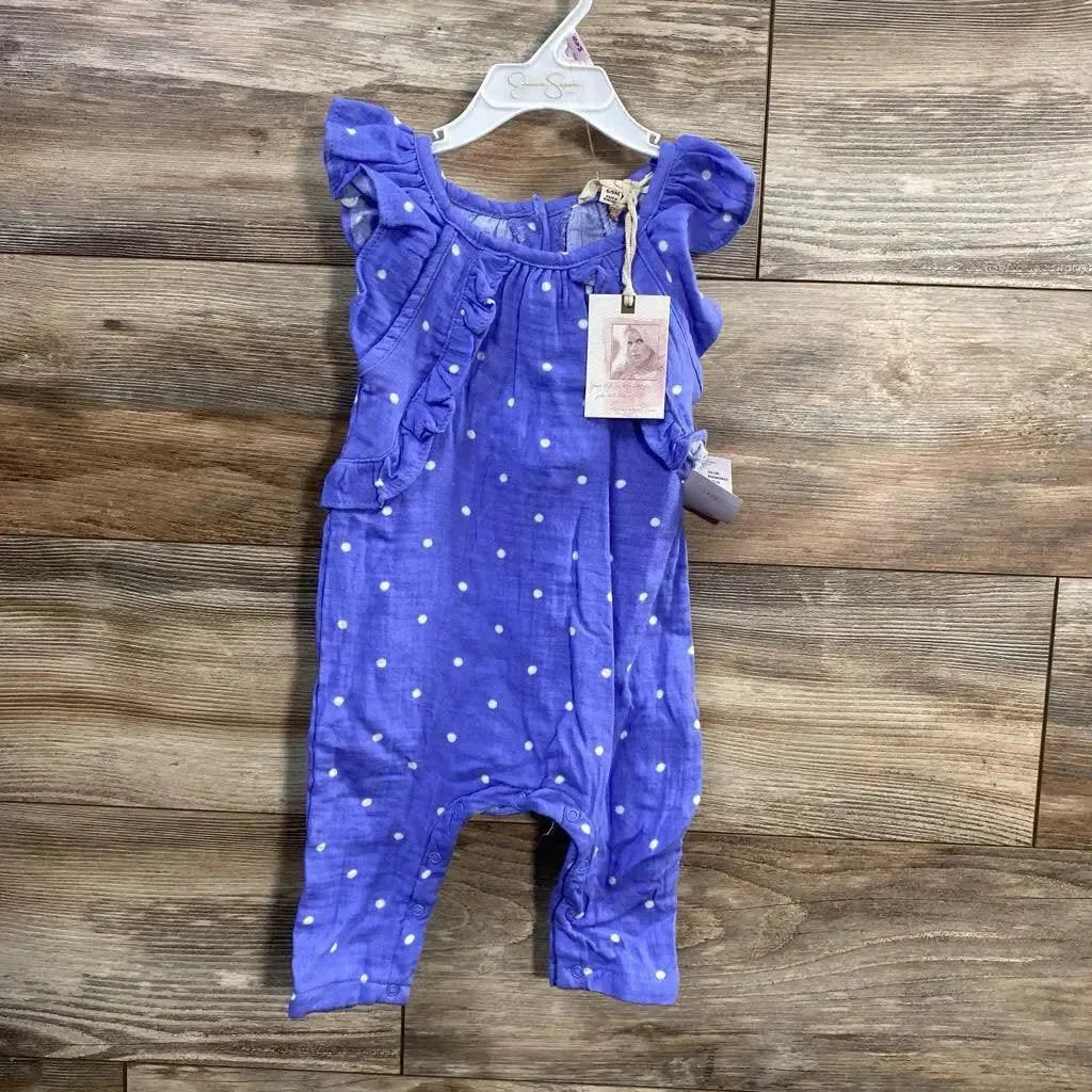 Front view of purple Jessica Simpson baby romper showcasing white polka dots and ruffle shoulder details on wood plank background