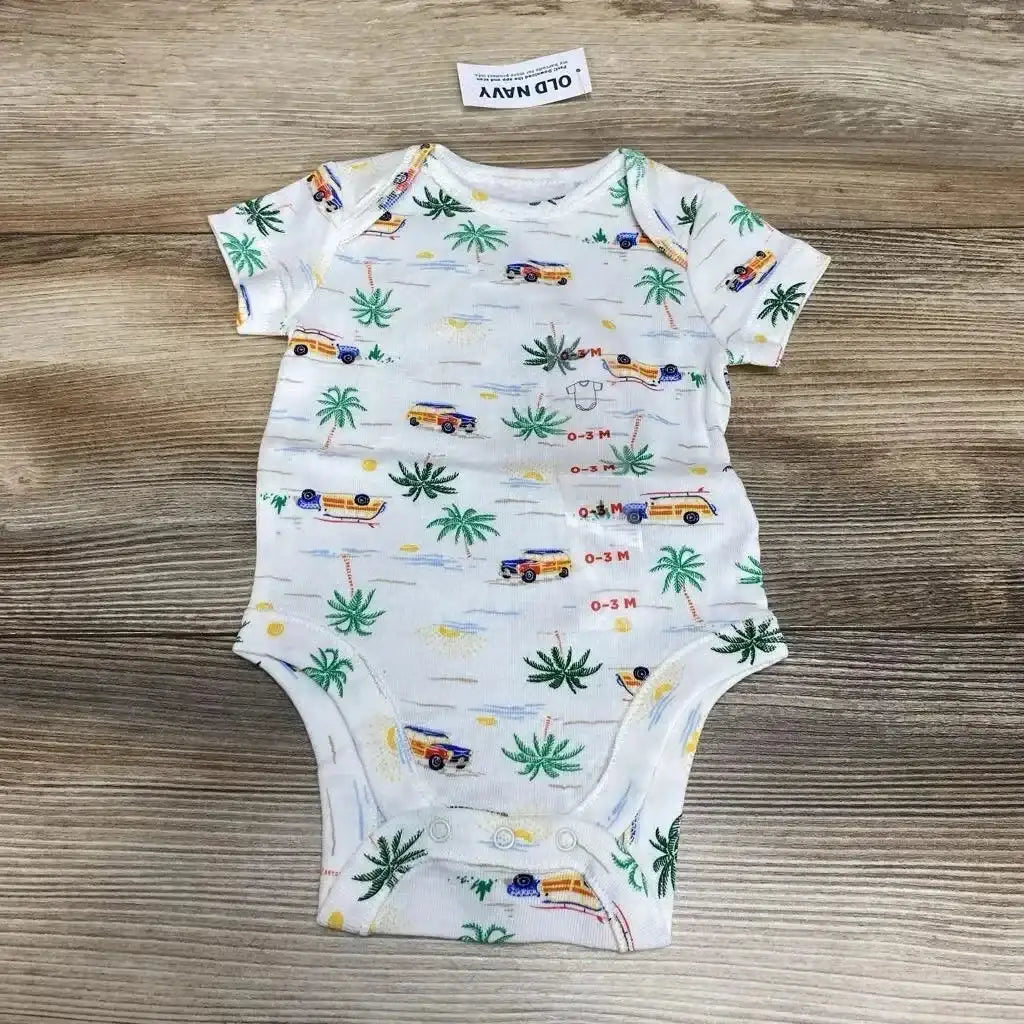 Flat-lay of white infant bodysuit 0-3M with navy beach-print vans and palm trees, snaps at crotch, on wood background