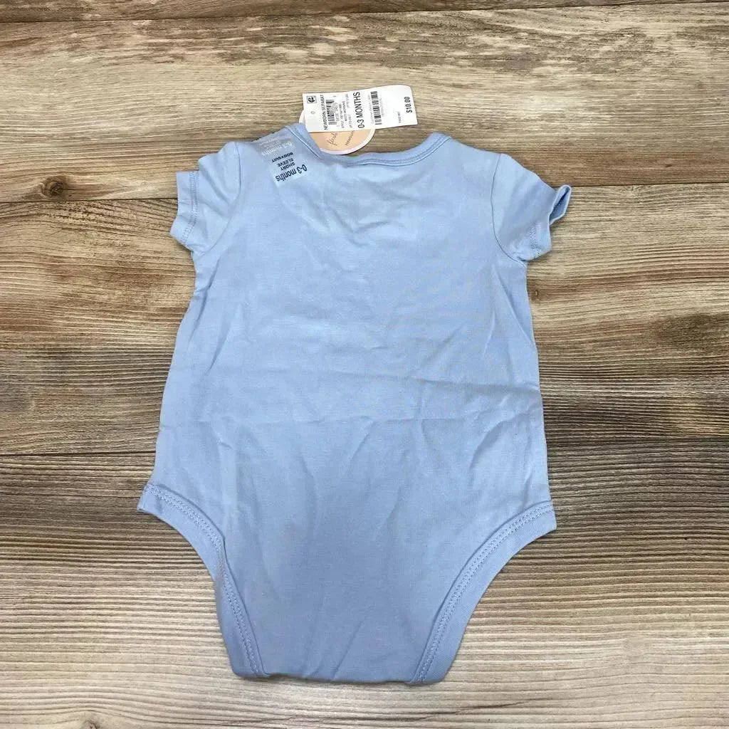 Back flat lay of light blue short-sleeve baby bodysuit showcasing retail tags and size 0-3M on a wood background