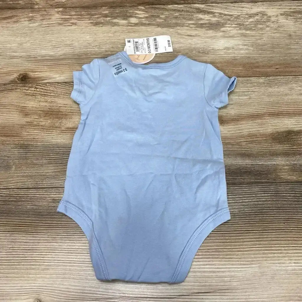 Back flat lay of light blue short-sleeve baby bodysuit showcasing retail tags and size 0-3M on a wood background