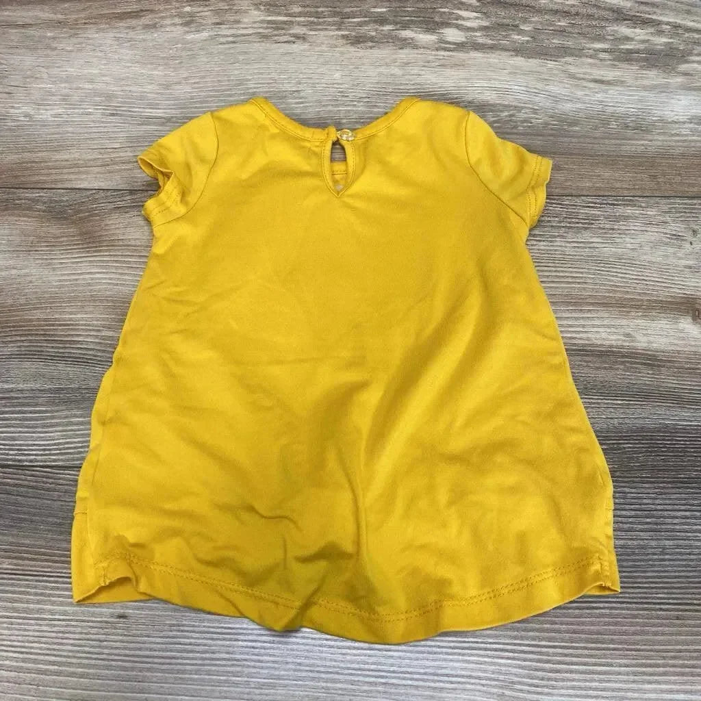 Back view of yellow Btween Sequin Fox toddler shirt (12 months) showcasing keyhole button closure and short sleeves on a wood floor background