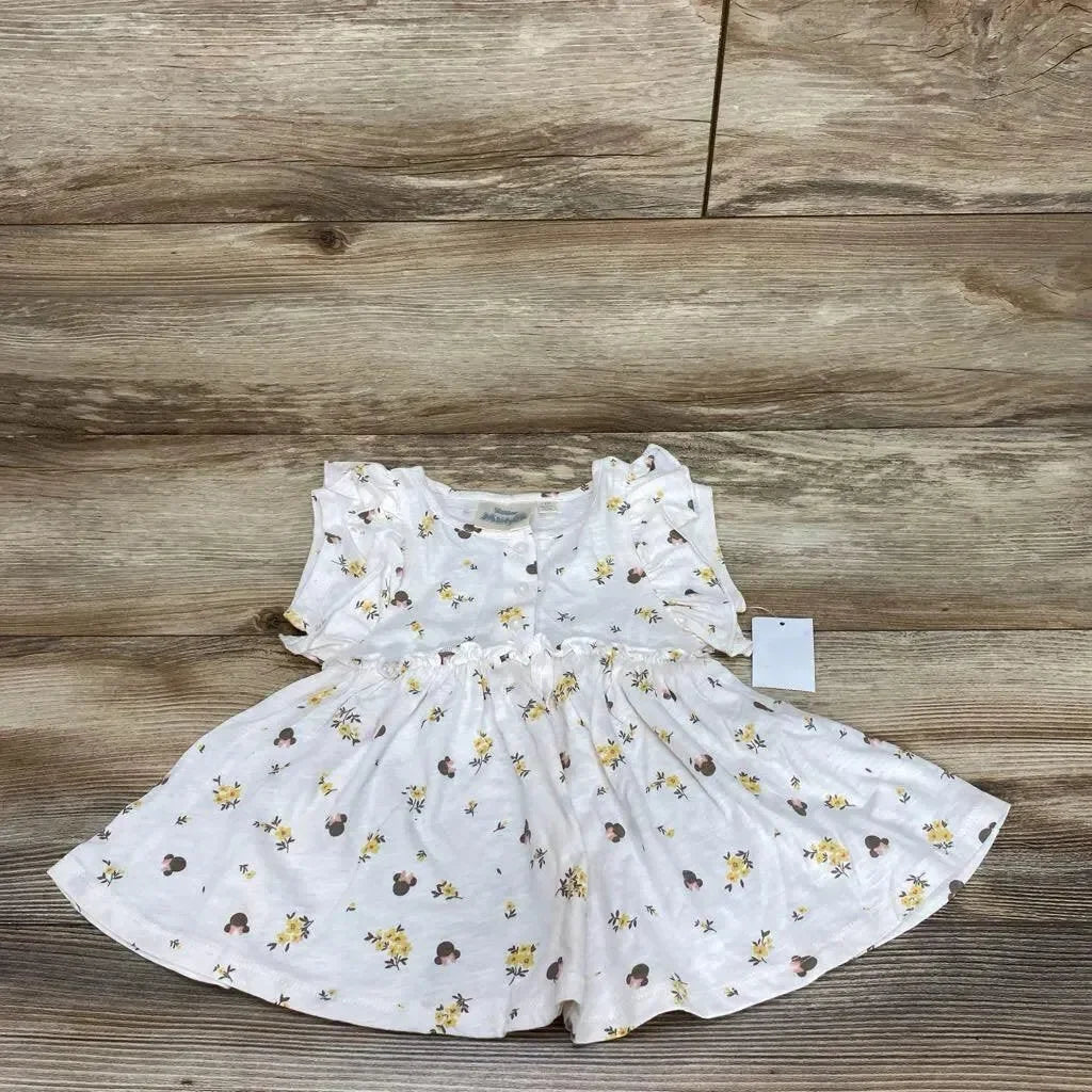 Flat lay of white Minnie floral henley dress size 12 months with ruffled sleeves and gathered skirt on wood background