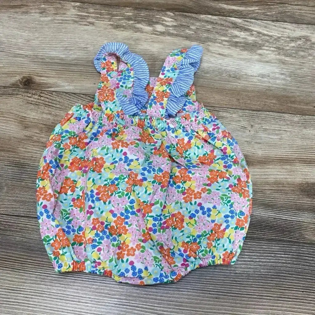 Flat lay of Baby Boden bubble romper with multicolored floral print, ruffled blue-striped straps, elastic hems on wood floor