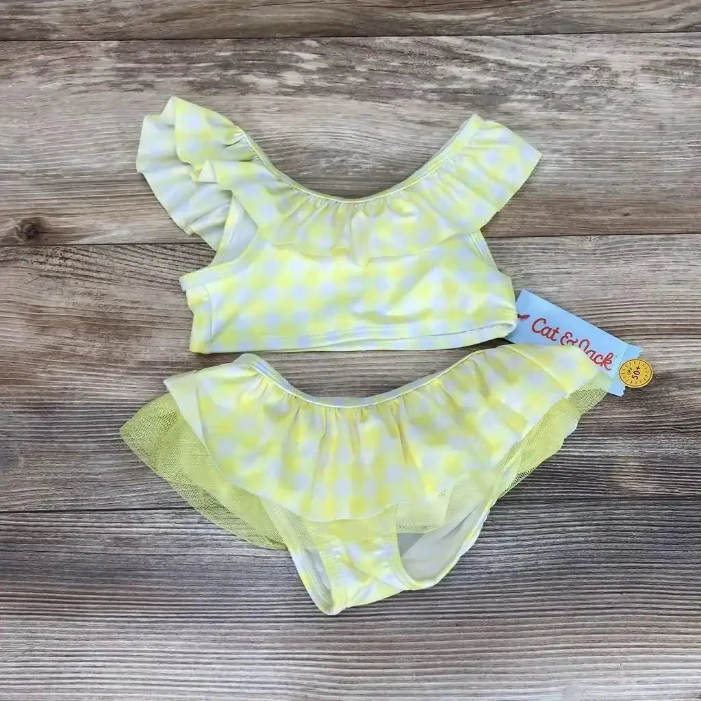 Top-down view of toddler 2T yellow gingham two-piece bikini showcasing ruffled neckline and tulle-skirted bottoms on wood background