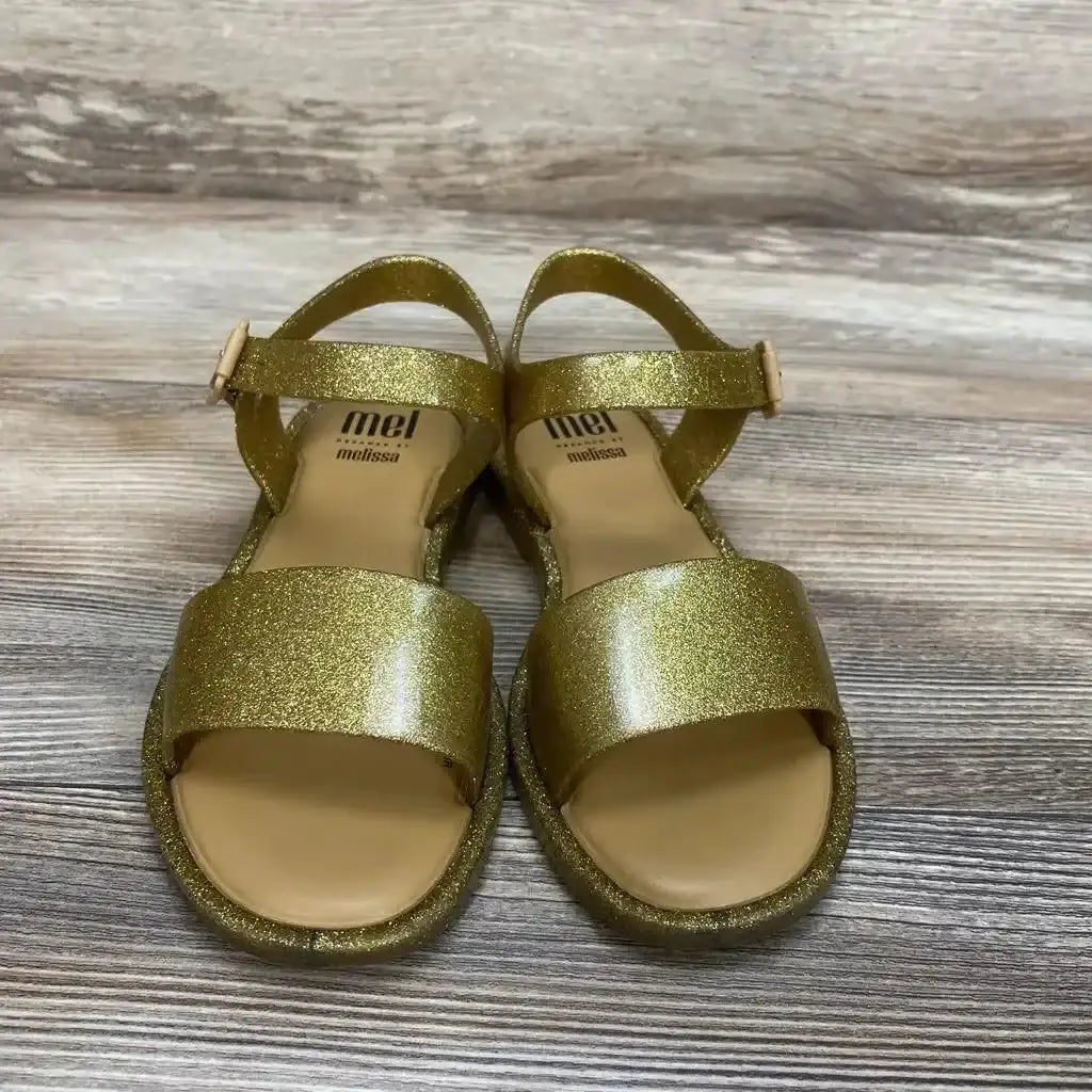 Three-quarter view of gold Mel By Melissa toddler jelly sandals, size 2Y, glitter finish on white background
