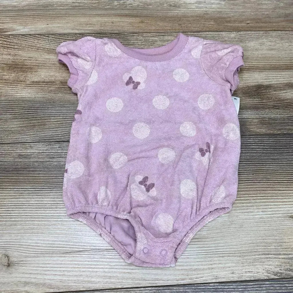 Flat lay of purple Minnie Mouse terry romper 0-3M showing white polka dots, bow motifs, puff sleeves and crotch snaps on wood background