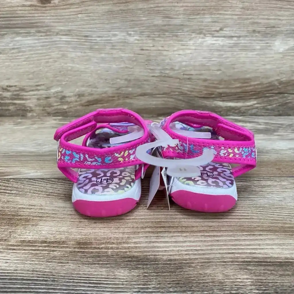 Front view of pink Paw Patrol ankle-strap sandals, size 11C, with patterned insoles and Velcro straps on wood surface