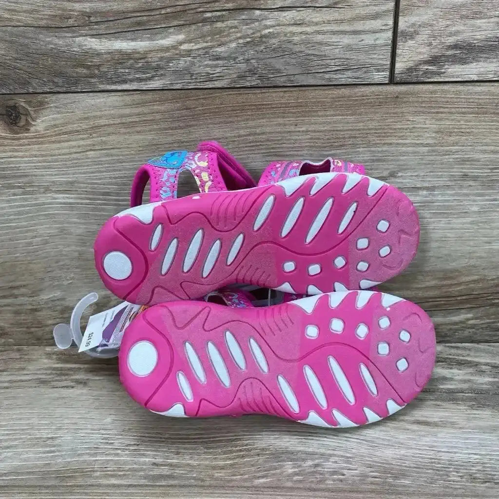 Bottom view of Paw Patrol ankle-strap toddler sandals showcasing pink treaded soles on wood plank background