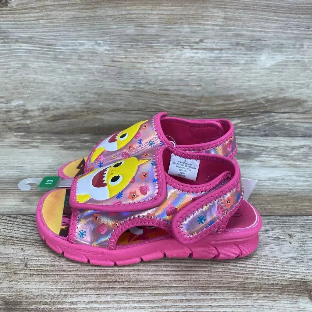 Side view of Pinkfong Baby Shark pink toddler water sandals size 10C with character print and Velcro straps on wood