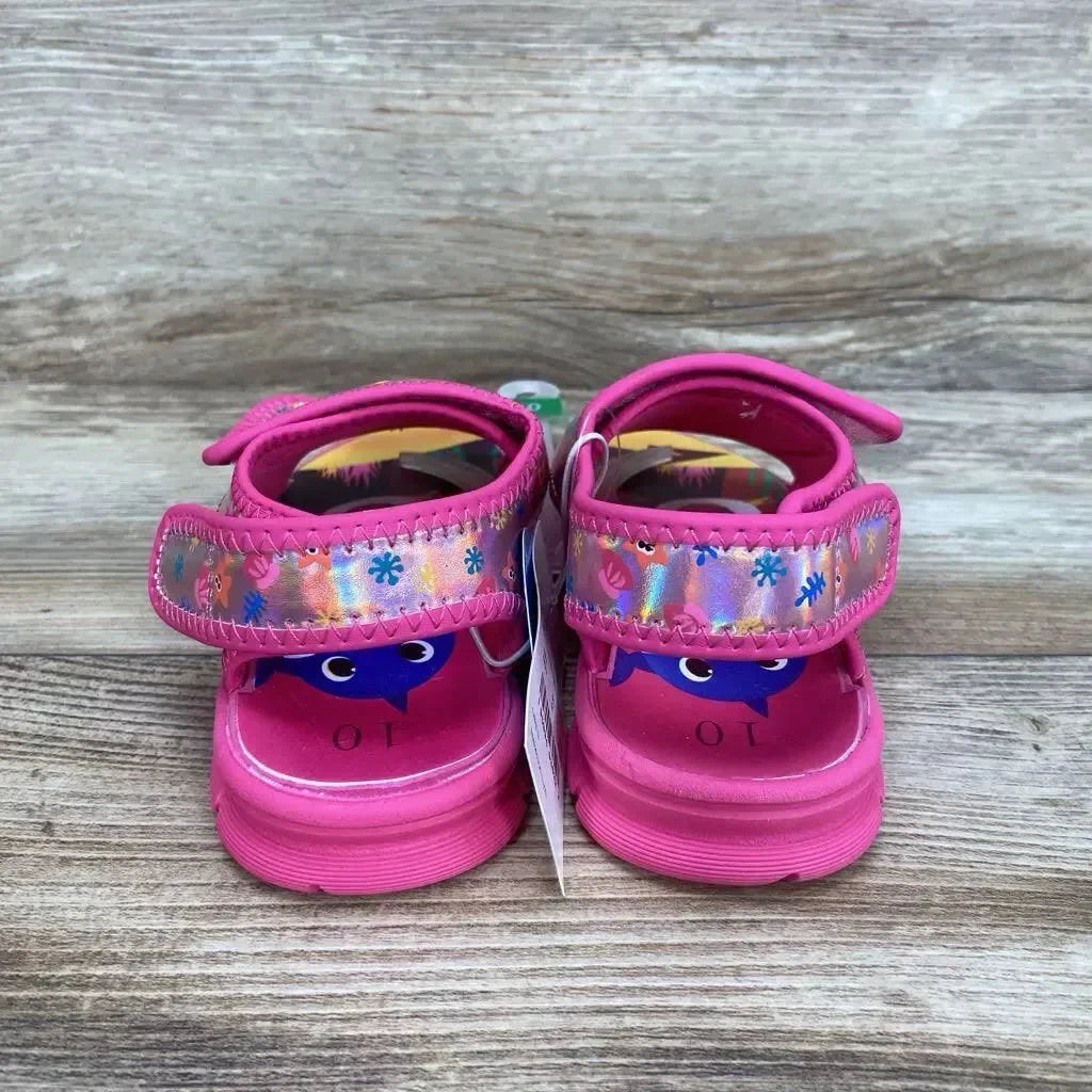 Rear view of pink Baby Shark toddler water sandals size 10C showcasing holographic floral Velcro straps and shark insole on wooden floor