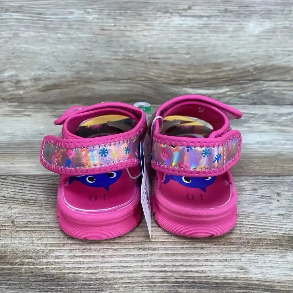 Back view of NEW Pinkfong Baby Shark Water Sandals sz 10c showcasing hot pink water sandals with holographic strap and shark print footbed on wood plank floor