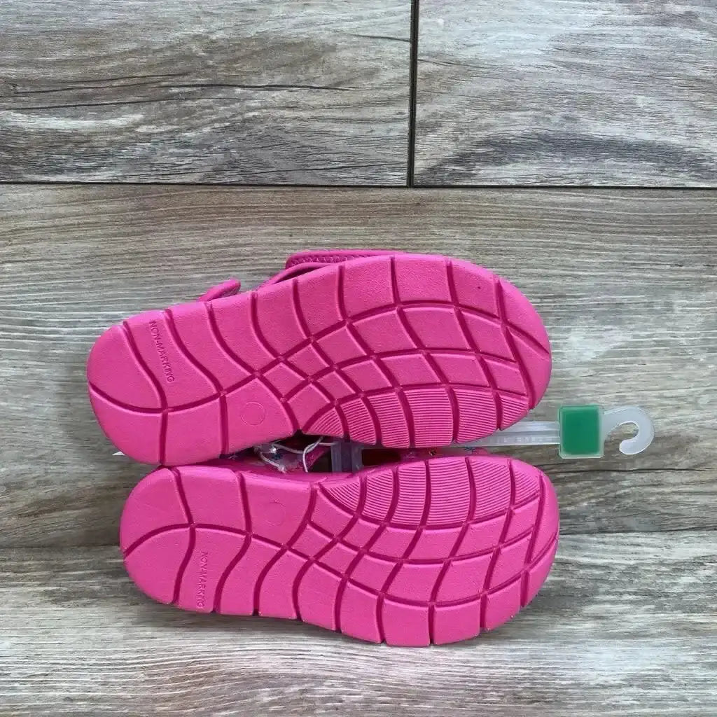 Underside view of Pinkfong Baby Shark pink water sandals (size 10C) showing textured non-slip soles on a wood floor