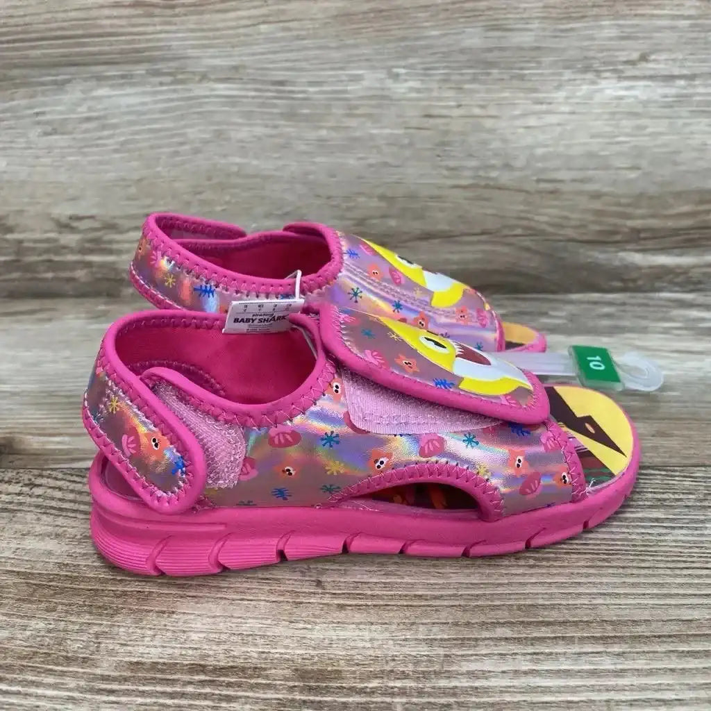Side view of pink Baby Shark water sandals (size 10C) showing Velcro strap, holographic seashell print and cushioned sole on wood background
