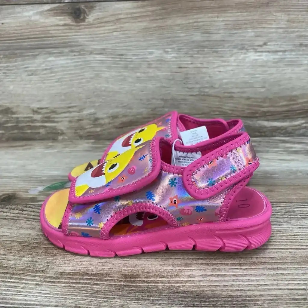 Side view of pink Baby Shark water sandal size 10c with velcro strap and cushioned sole on wood background