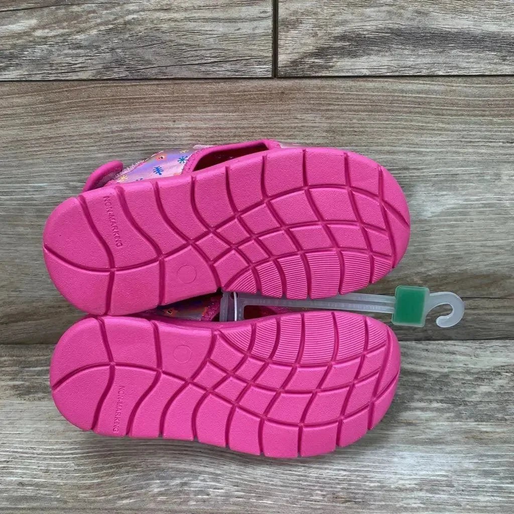 Top view of Pinkfong Baby Shark pink water sandals with textured non-slip soles and Velcro straps on wood background