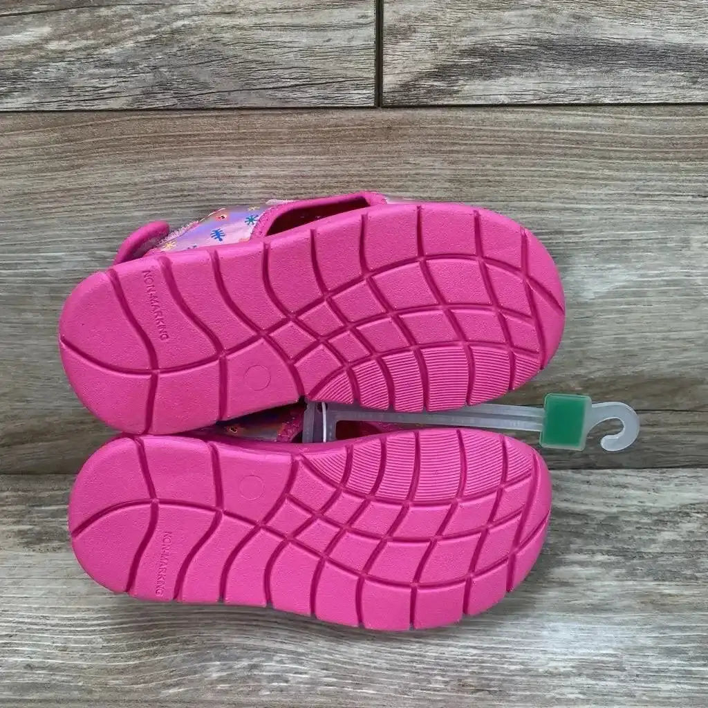 Bottom view of Pinkfong Baby Shark water sandals in pink showcasing textured non-slip soles with double Velcro closure on wood flooring