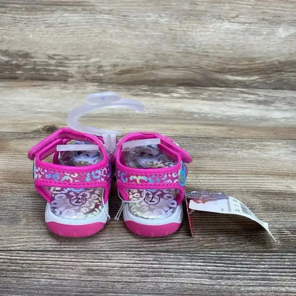 Rear view of pink Paw Patrol ankle-strap toddler sandals showing Velcro straps and character insole on wood background