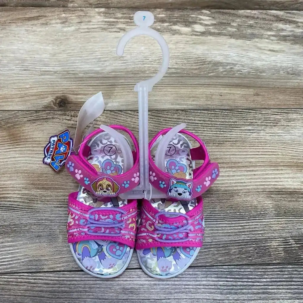 Top view of pink Paw Patrol toddler ankle-strap sandals size 7C showing character appliques and Velcro straps on wood floor