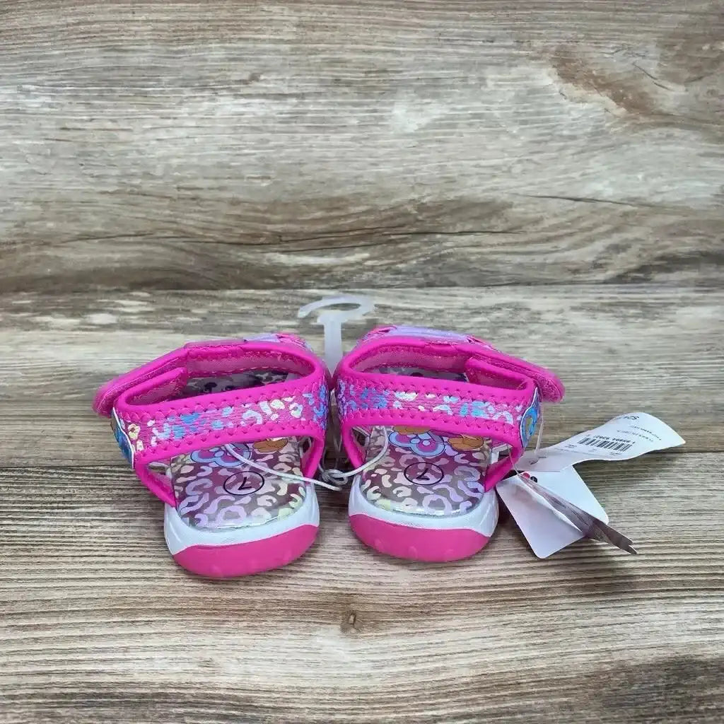 Front view of pink Paw Patrol ankle-strap sandals size 7C with sequined straps and patterned footbeds on wood table