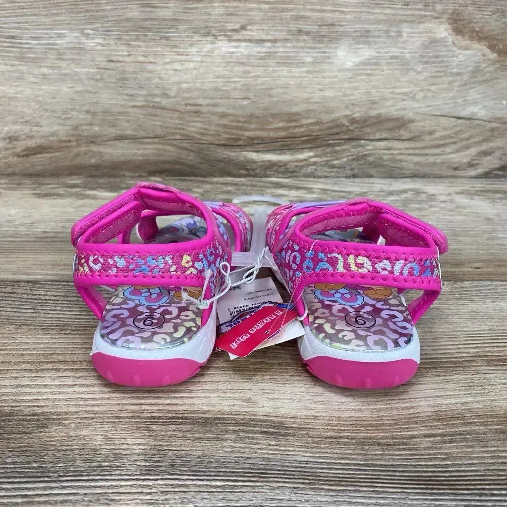 Rear view of pink Paw Patrol toddler ankle-strap sandals size 9C showcasing floral-patterned footbed and glitter pink hook-and-loop straps on wood background