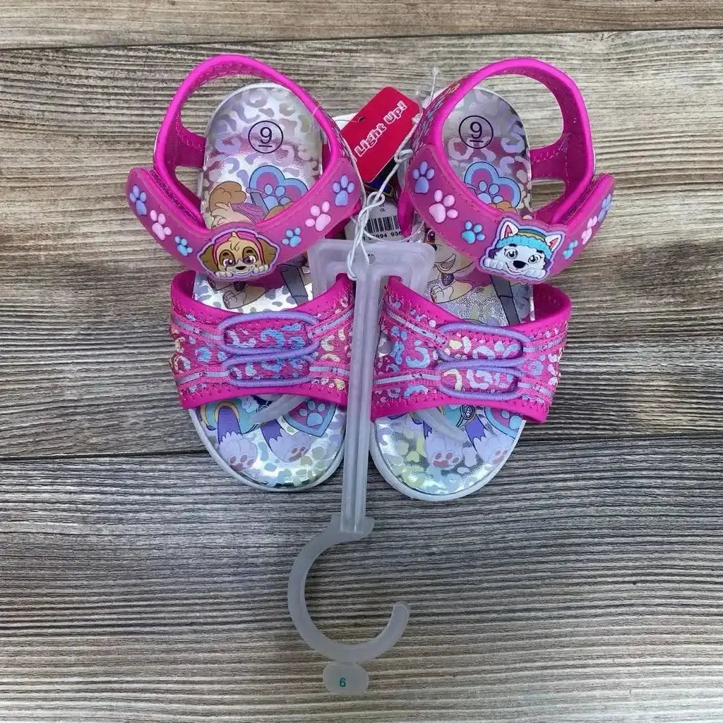 Top view of pink Paw Patrol ankle-strap sandals with character icons, paw-print Velcro straps, size 9 visible on insole