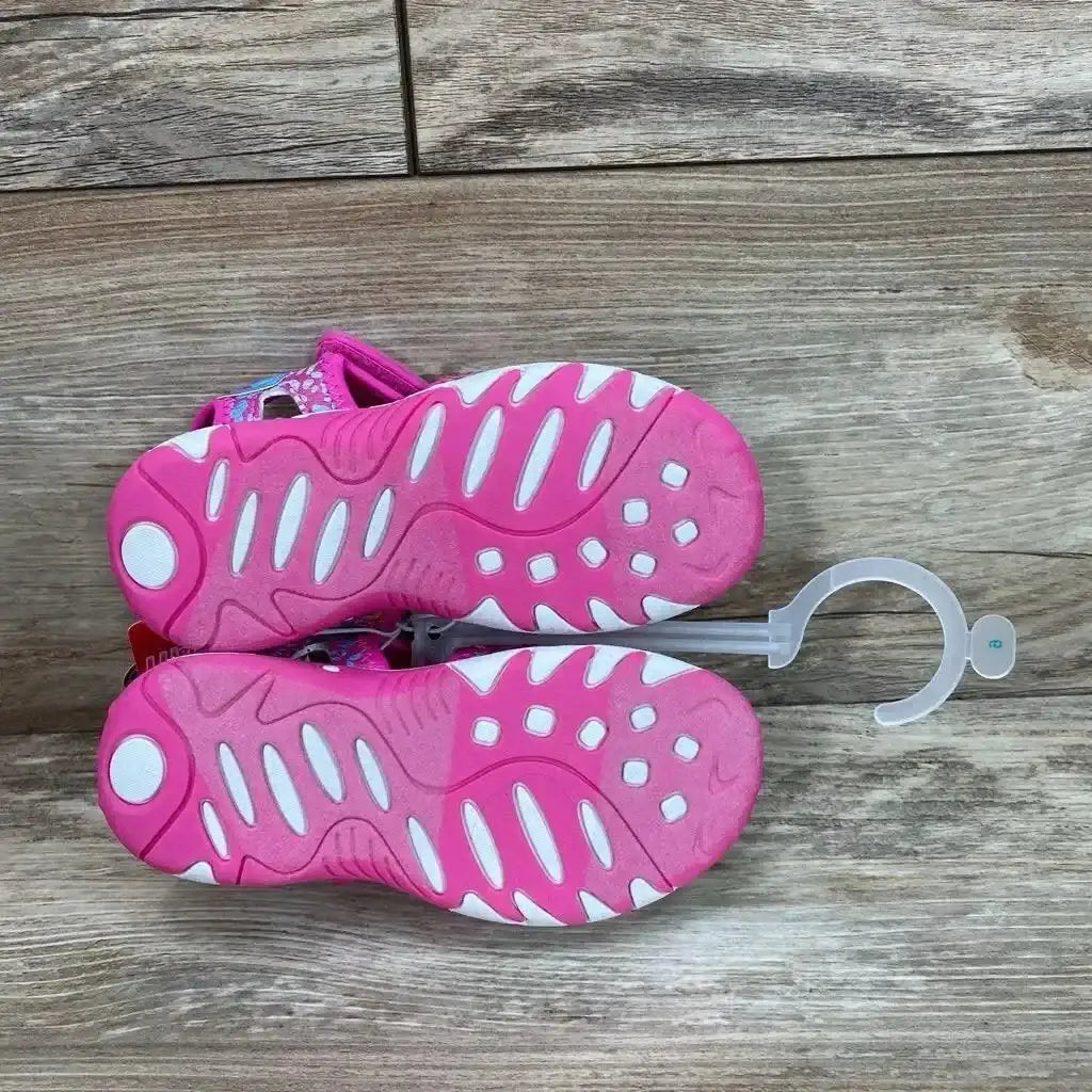 Top view of pink Paw Patrol ankle-strap sandals 9C showing white-accented treads and Velcro straps on wood floor