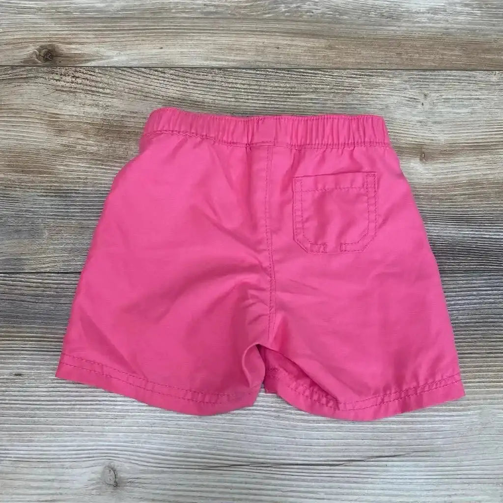 Back view of pink Old Navy swim shorts (12–18M) showcasing elastic waistband and back pocket on light wood background