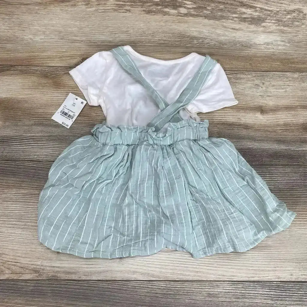 Top-down of white shirt with mint-green striped suspender skirt, crisscross straps and ruffled waist on wood floor
