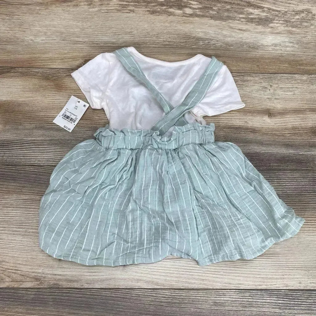 Top-down of white shirt with mint-green striped suspender skirt, crisscross straps and ruffled waist on wood floor