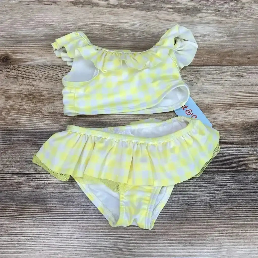 Flat lay of NEW Cat and Jack two piece bikini set in yellow gingham with ruffle top and ruffle skirted bottom on wood plank floor