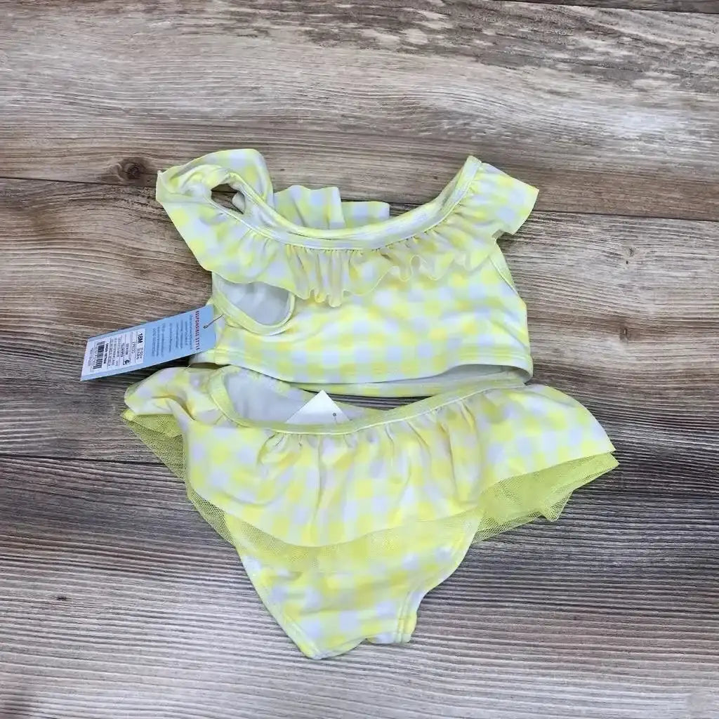 Top down view of yellow gingham baby bikini 18m with ruffled off shoulder top and tulle trim ruffle bottoms on wood background