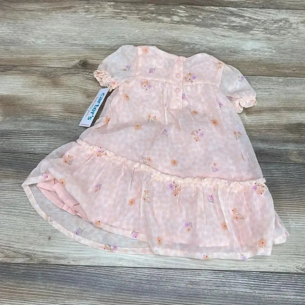 Flat lay of pink floral baby dress and matching bloomers showing puff sleeves and ruffled hem on wood background