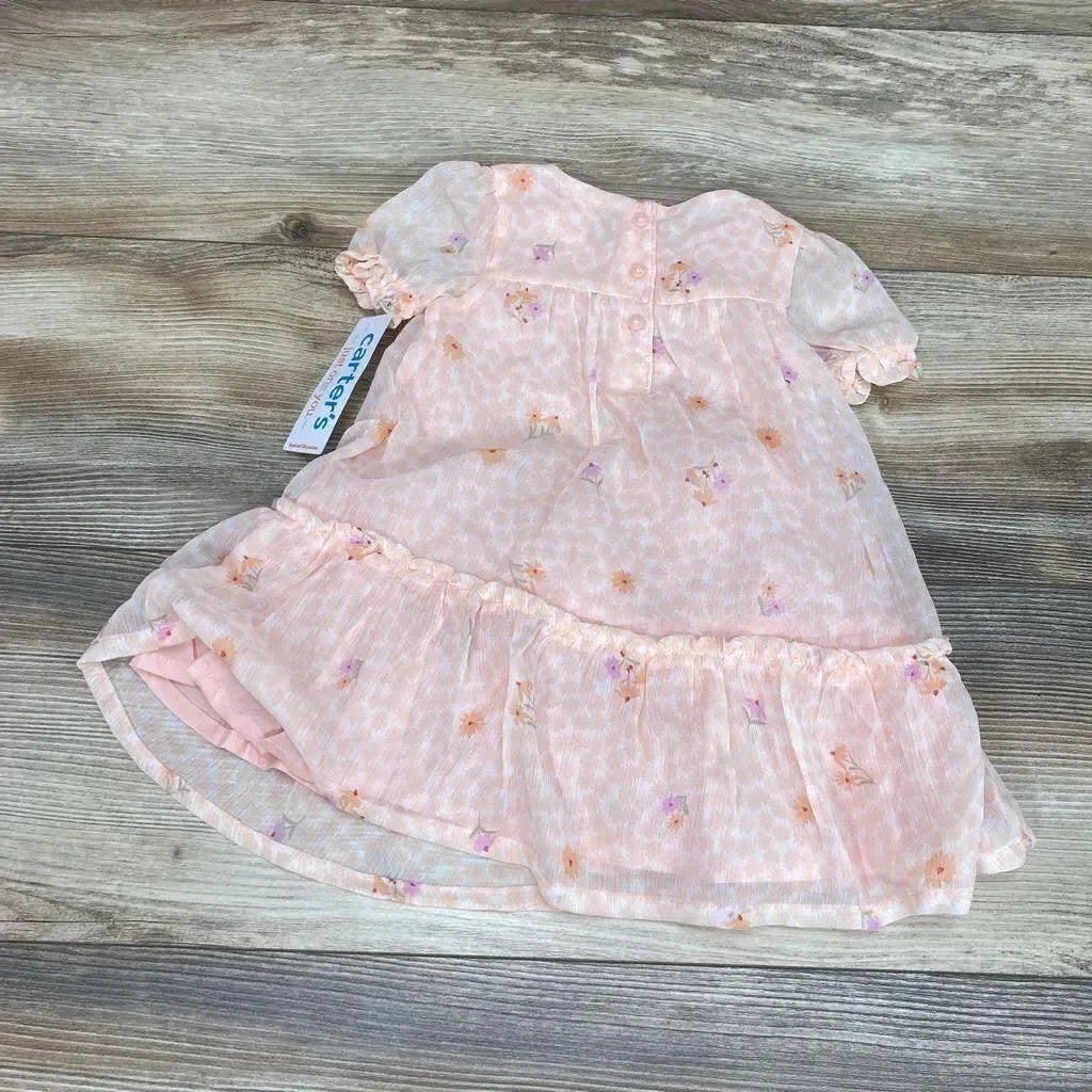 Flat lay of pink floral baby dress and matching bloomers showing puff sleeves and ruffled hem on wood background