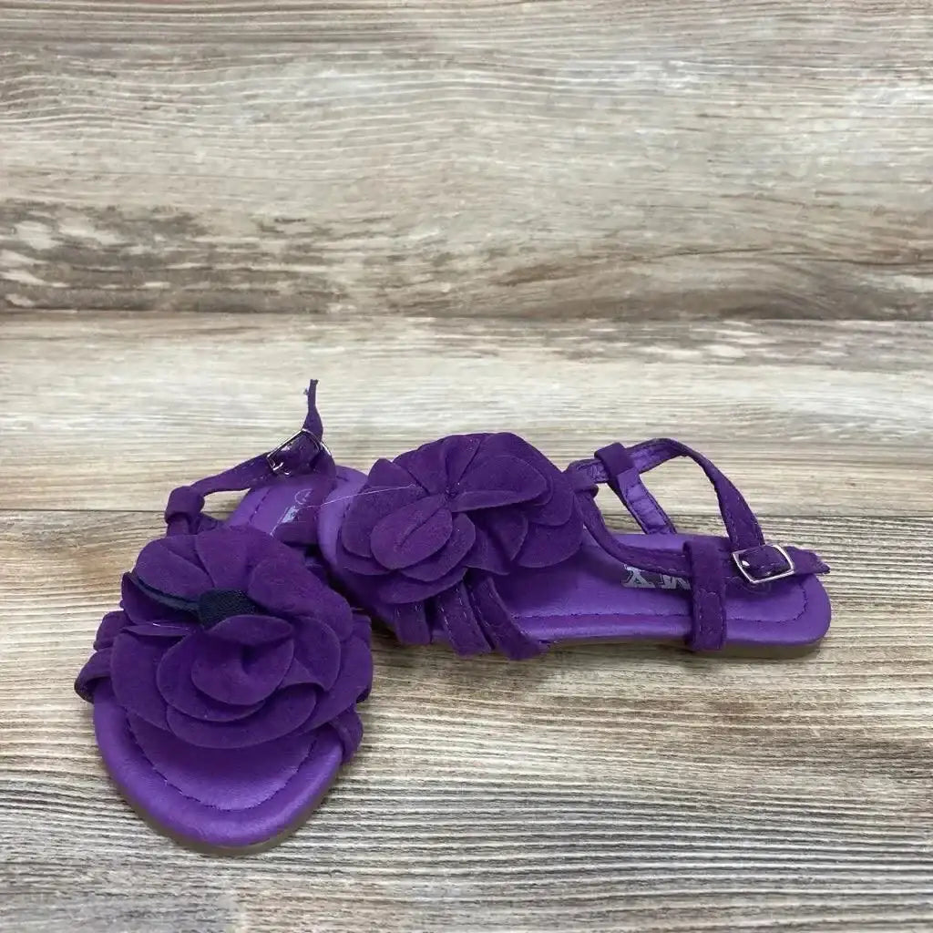 Three-quarter view of purple toddler strappy sandals with layered flower embellishments and ankle buckle, size 5C, on wooden background