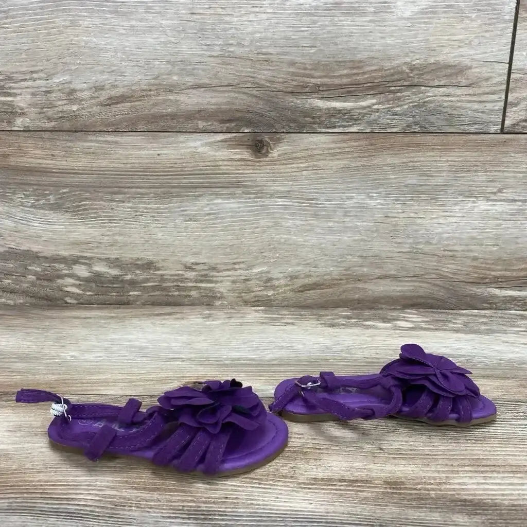 Side view of Amy strappy flower sandals in purple with petal embellishment and ankle buckle strap on wood plank floor