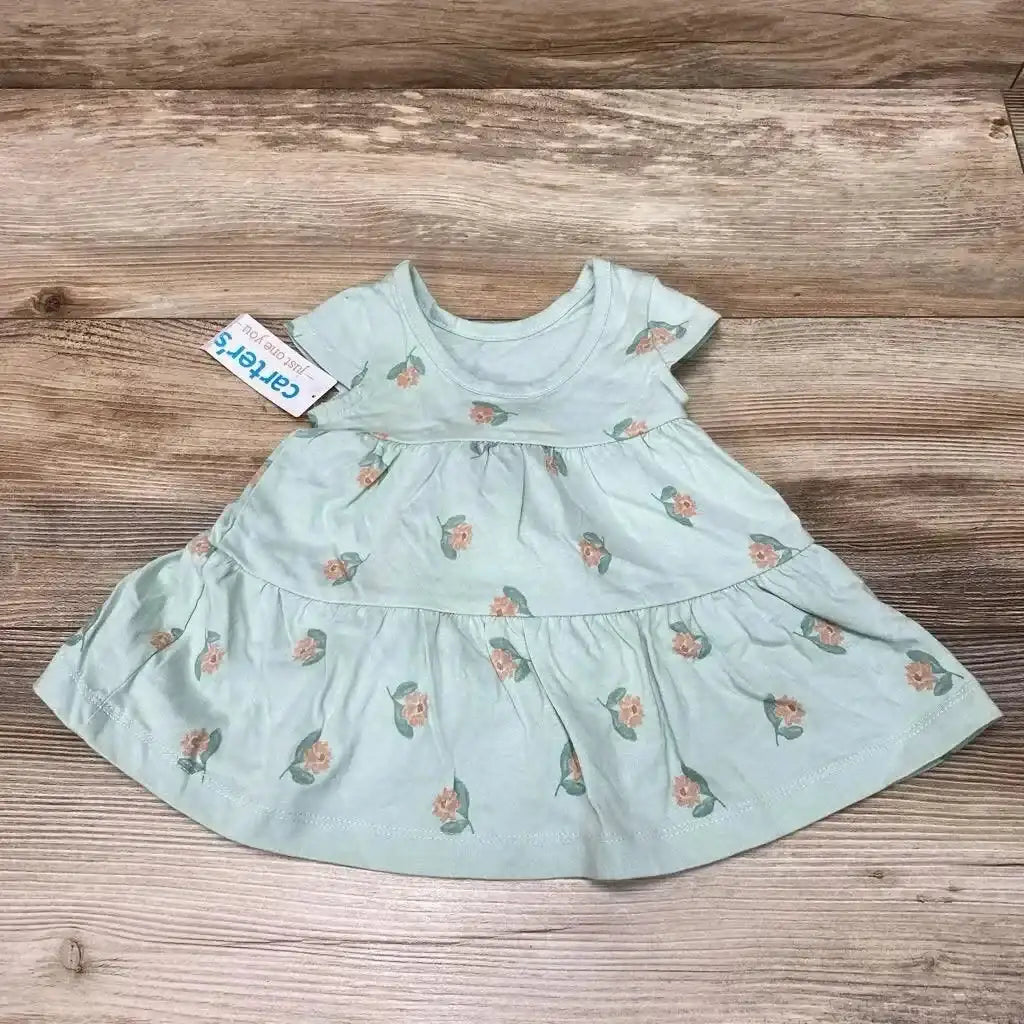 Flatlay of mint green floral baby dress showing short sleeves and tiered skirt on wooden background