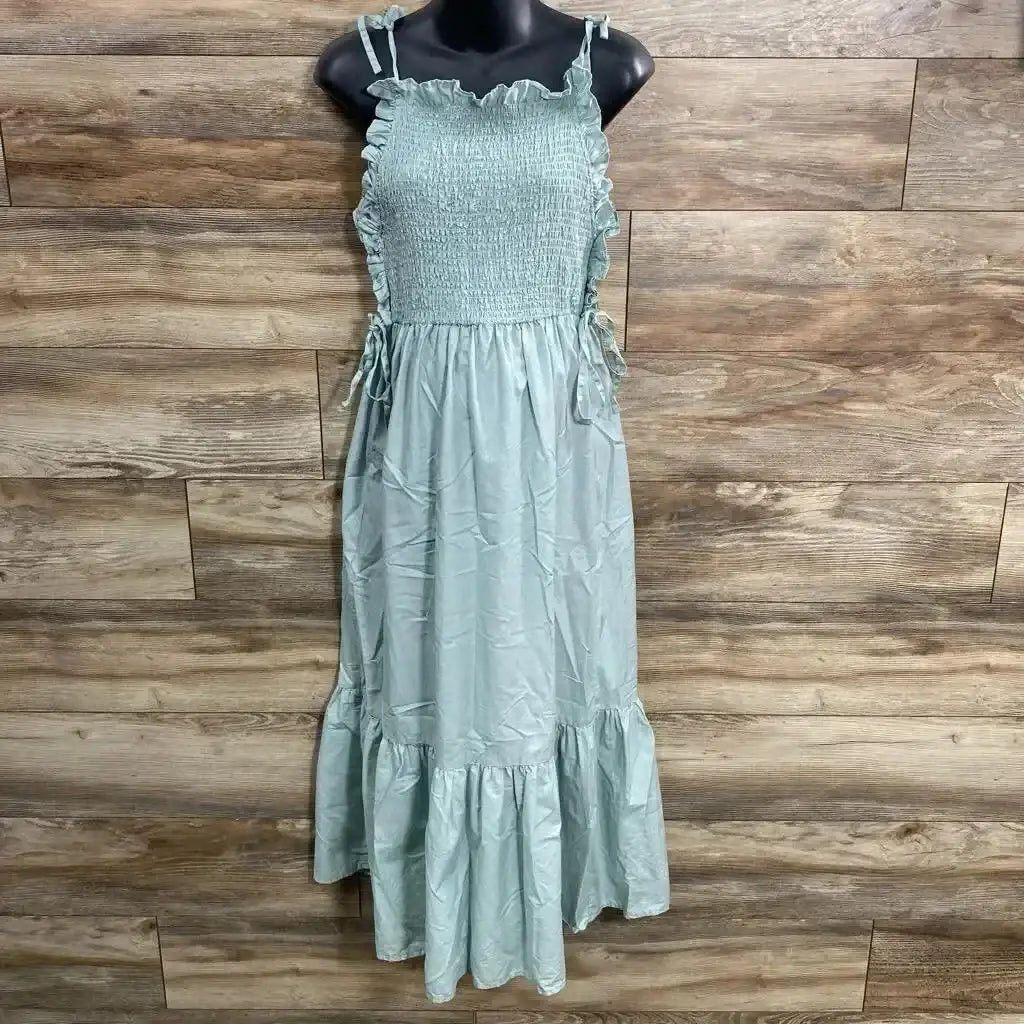 Front view of green Asos maternity smocked maxi dress with tie shoulder straps and ruffle hem on mannequin, wood background