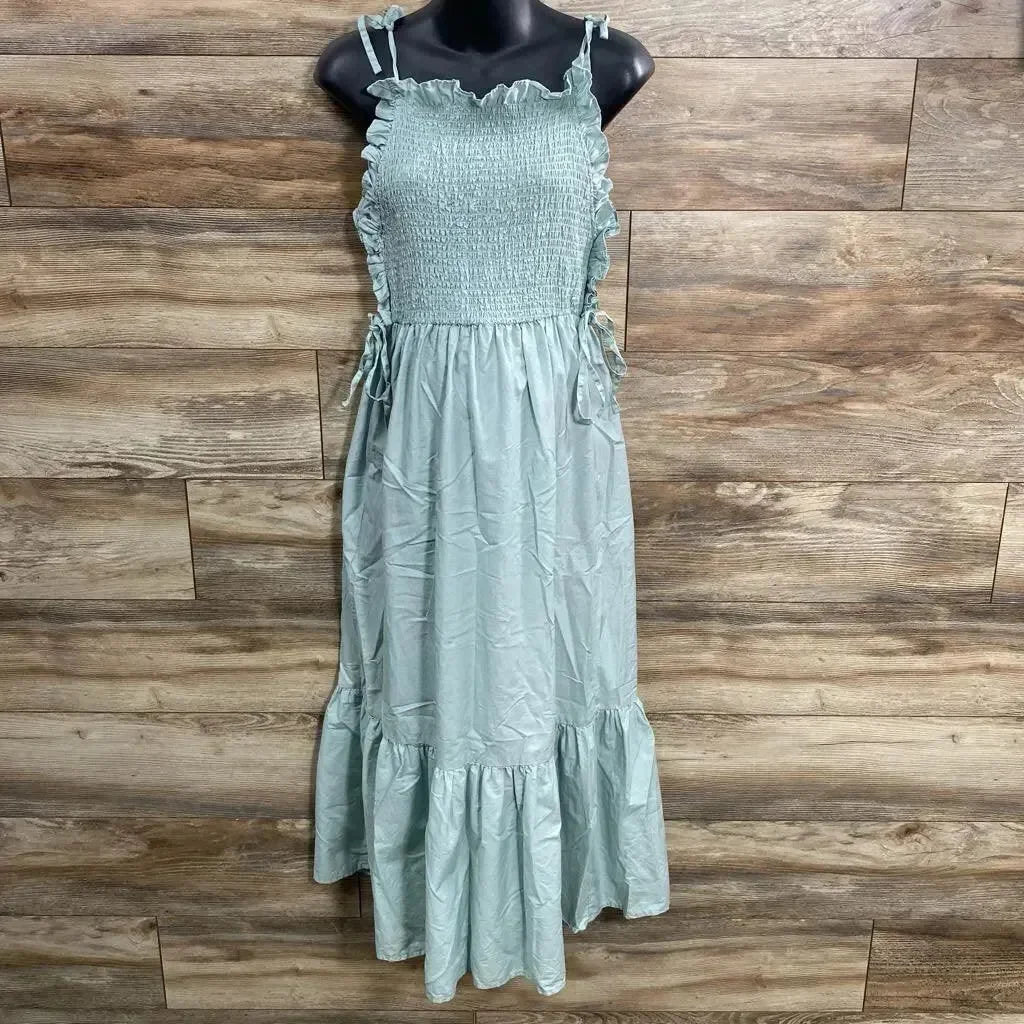 Front view of green Asos maternity smocked maxi dress with tie shoulder straps and ruffle hem on mannequin, wood background