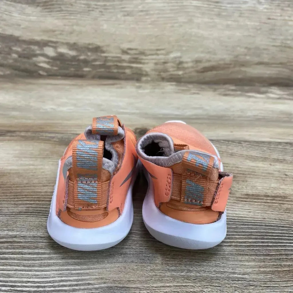 Rear view of orange Nike Flex Runner toddler sneakers showcasing pull tabs and hook-and-loop straps with white soles on a wood floor