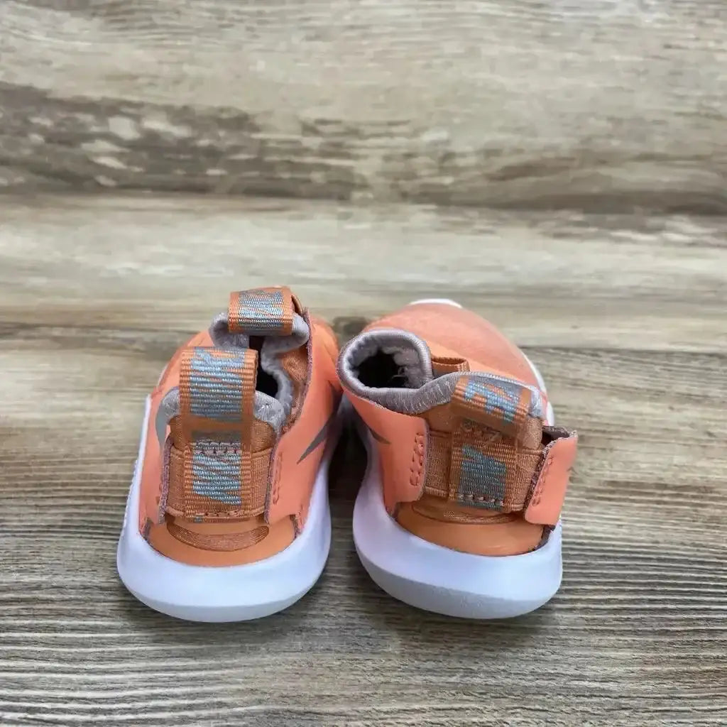 Rear view of orange Nike Flex Runner toddler sneakers showcasing pull tabs and hook-and-loop straps with white soles on a wood floor