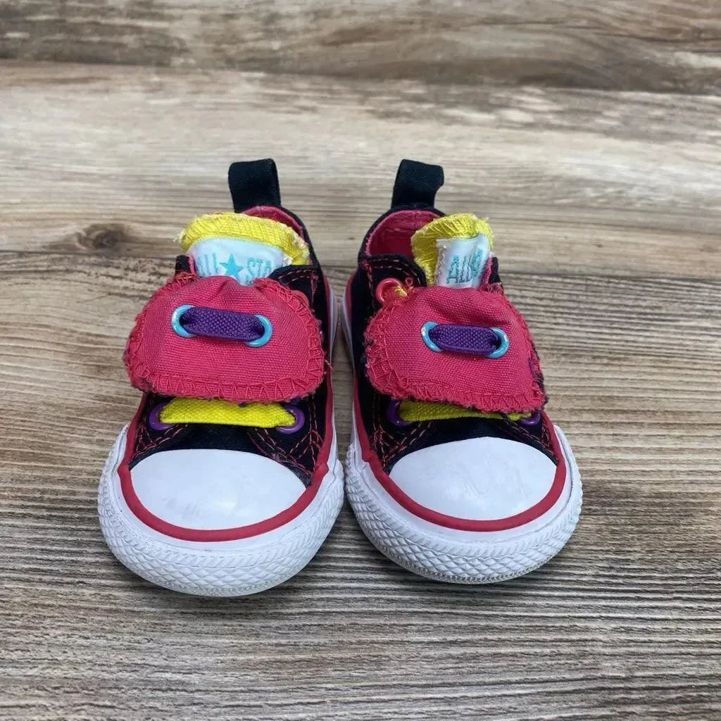Front view of used toddler black Converse double-tongue low-top sneakers size 3C showing colorful tongues on wood background
