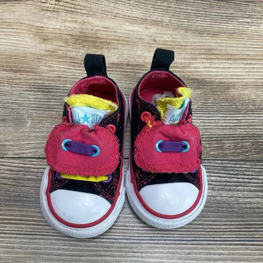Top view of toddler Converse Chuck Taylor double-tongue sneakers size 3C, white toe caps and multicolor accents on wood floor