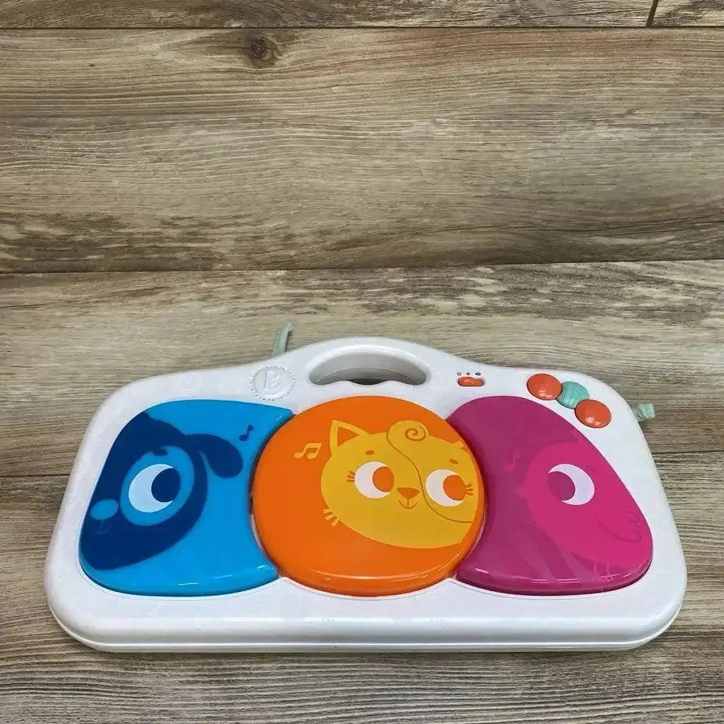 Top view of B. Toys Musical Party Dance Pad showcasing white pad with blue dog orange cat and pink owl buttons on wood plank floor