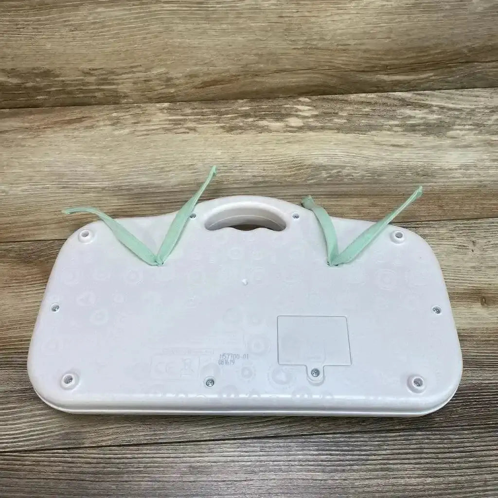 Back of B. Toys dance pad showing carry handle, battery compartment and mint tie straps on wood background