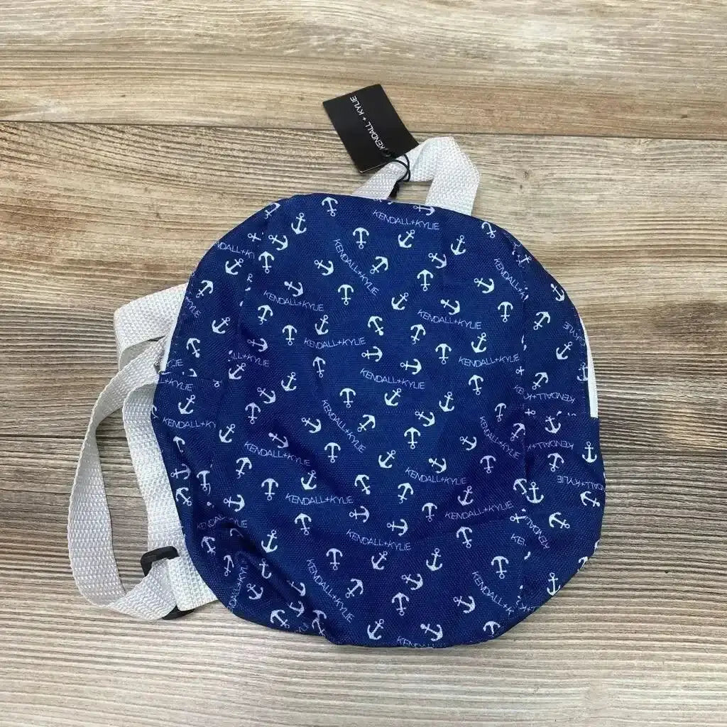 Top-down view of blue Kendall + Kylie micro mini backpack with white anchor pattern and white straps on light wood