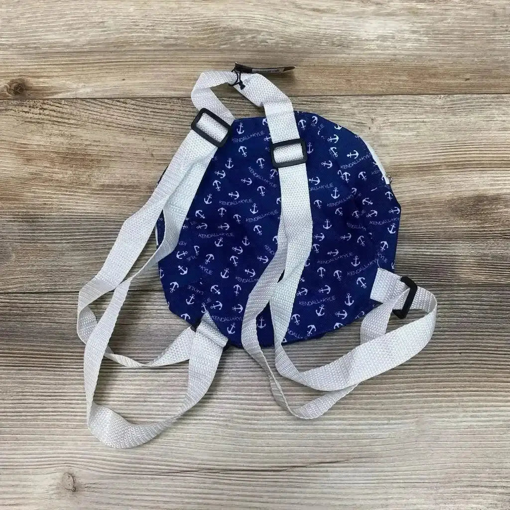Top-down view of navy Kendall + Kylie micro mini backpack showing white anchor print, white adjustable straps, and round shape on a light wood background