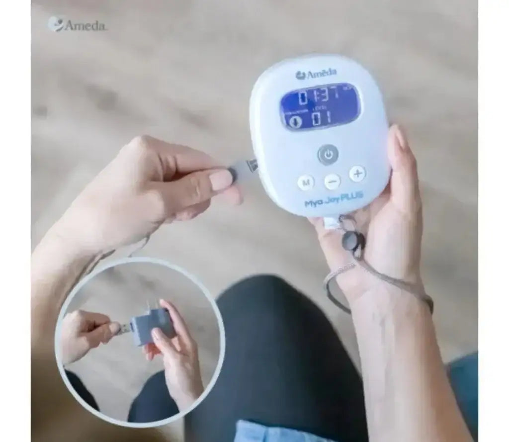Top-down view of Mya hospital-strength double electric breast pump handheld unit showing LCD display and control buttons on a wood floor background