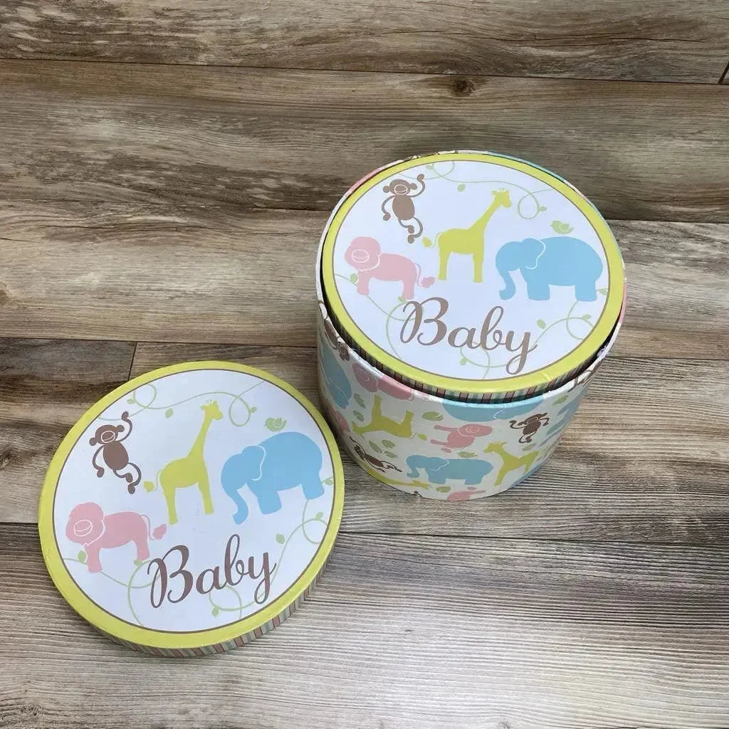 Top-down view of round nesting storage trunks with pastel animal print and Baby on lids, one lid removed on wood floor