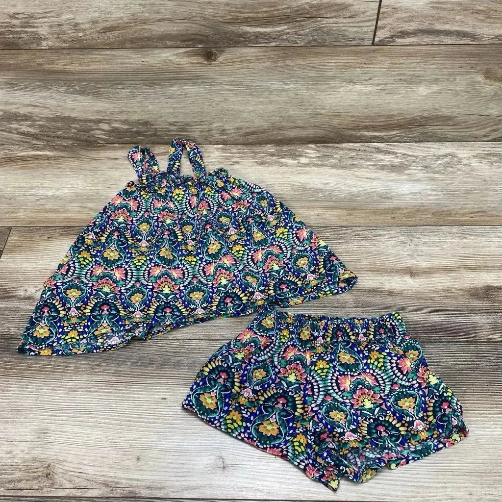 Flat lay of baby sleeveless top and shorts with multicolored floral print and elastic-waist, on wood background